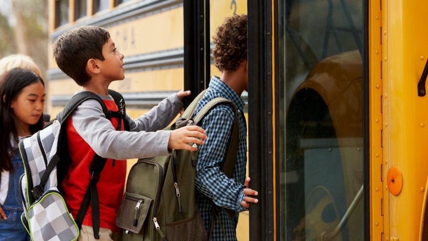 Photo of school aged children getting on a bus